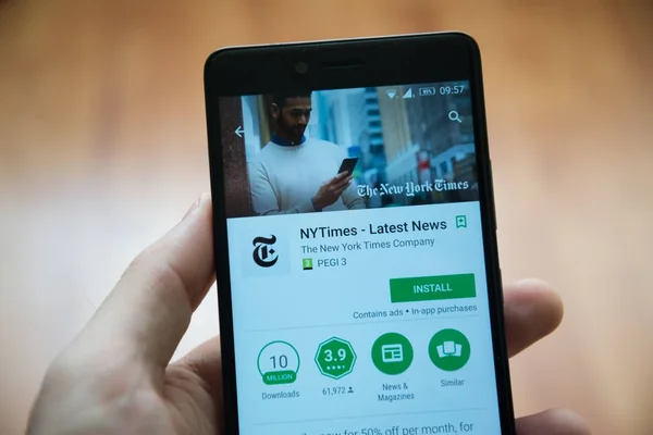Мужчина держит в руках смартфон с приложением New York Times в магазине игр google — стоковое фото
