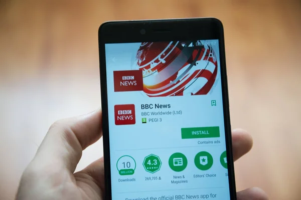 Muž držel smartphone s Bbc News aplikace v obchodě google play — Stock fotografie