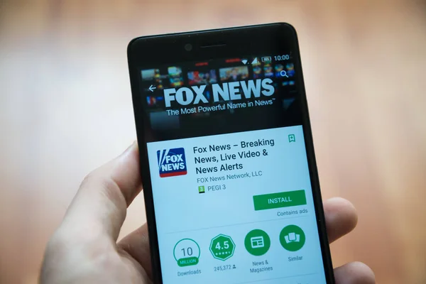 Мужчина держит в руках смартфон с приложением Fox News в магазине игрушек google — стоковое фото