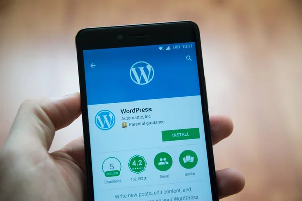 Человек держит смартфон с приложением Wordpress в Google Play Store — стоковое фото