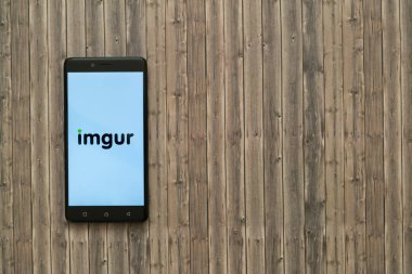 Imgur logo üstünde smartphone perde ahşap arka plan üzerinde.
