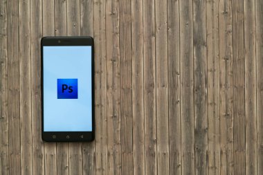 Adobe photoshop logo üstünde smartphone perde ahşap arka plan üzerinde.