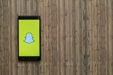 Snapchat logo üstünde smartphone perde ahşap arka plan üzerinde.