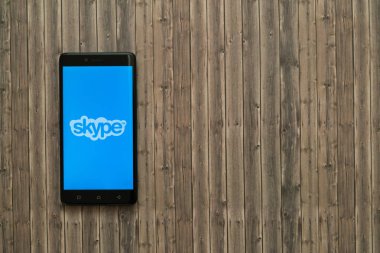 Skype logo üstünde smartphone perde ahşap arka plan üzerinde.