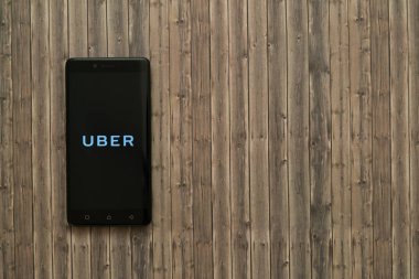 Uber logo üstünde smartphone perde ahşap arka plan üzerinde.