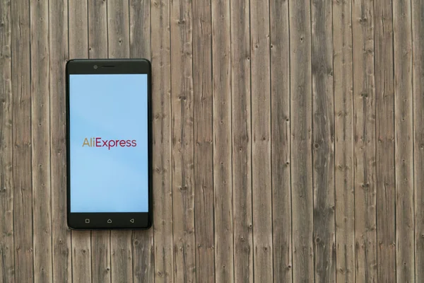 Aliexpress логотип на екрані смартфона на фоні дерев'яні. — стокове фото