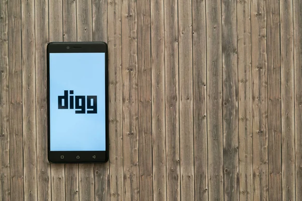 Digg logo na ekranie smartfona na podłoże drewniane. — Zdjęcie stockowe