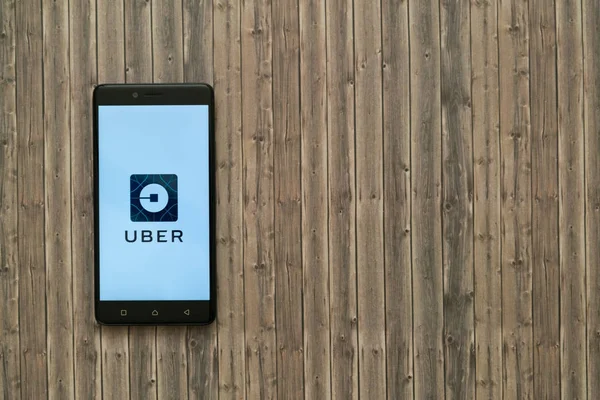 Logotipo Uber na tela do smartphone em fundo de madeira . — Fotografia de Stock