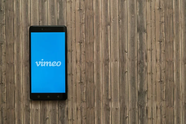 Logo de Vimeo en la pantalla del smartphone sobre fondo de madera . — Foto de Stock