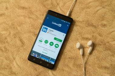 LinkedIn uygulama Google oyun deposu kumlu arka plan ve kulaklıklar üzerinde