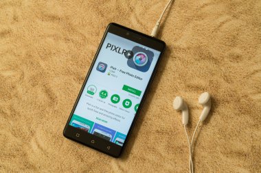 Pixlr uygulama Google oyun deposu kumlu arka plan ve kulaklıklar üzerinde