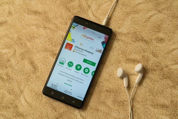 Aplicación Aliexpress en Google Play Store sobre fondo arenoso y auriculares — Foto de Stock