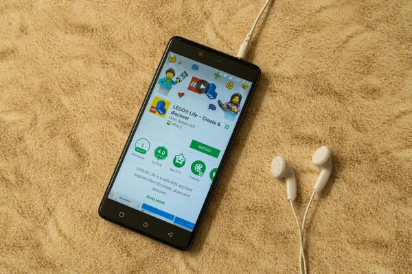 Lego life application in google play store on sandy background and earphones — Stock Photo, Image