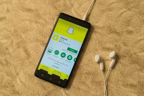 Snapchat uygulama Google oyun deposu kumlu arka plan ve kulaklıklar üzerinde — Stok fotoğraf