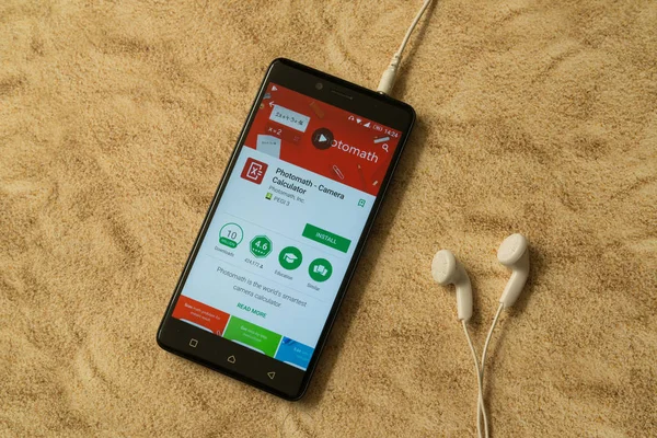 Aplicación Photomath en Google Play Store sobre fondo arenoso y auriculares — Foto de Stock