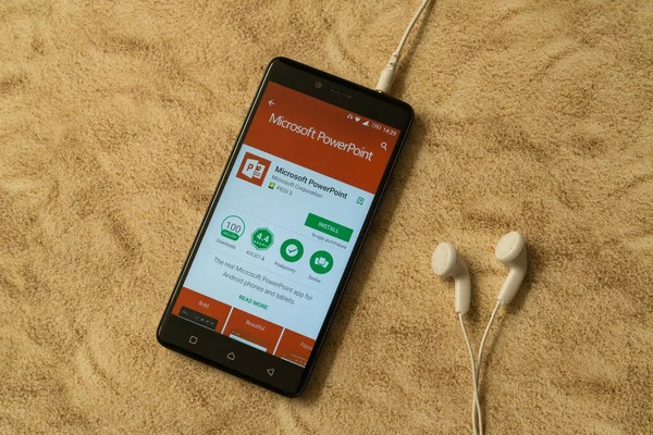Microsoft Powerpoint-Anwendung im Google Play Store auf sandigem Hintergrund und Kopfhörer — Stockfoto