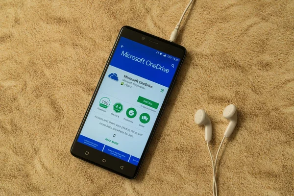 Microsoft onedrive Anwendung in Google Play Store auf sandigem Hintergrund und Kopfhörer — Stockfoto