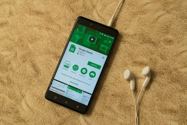 Aplicación de hojas de Google en Google Play Store sobre fondo arenoso y auriculares — Foto de Stock