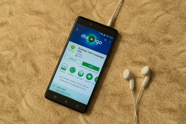 Aplicación Duiloingo en Google Play Store sobre fondo arenoso y auriculares — Foto de Stock