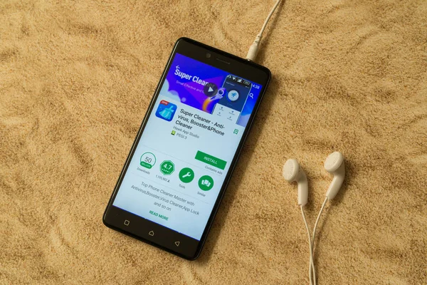 Super Cleaner-Anwendung in Google Play Store auf sandigem Hintergrund und Kopfhörer — Stockfoto