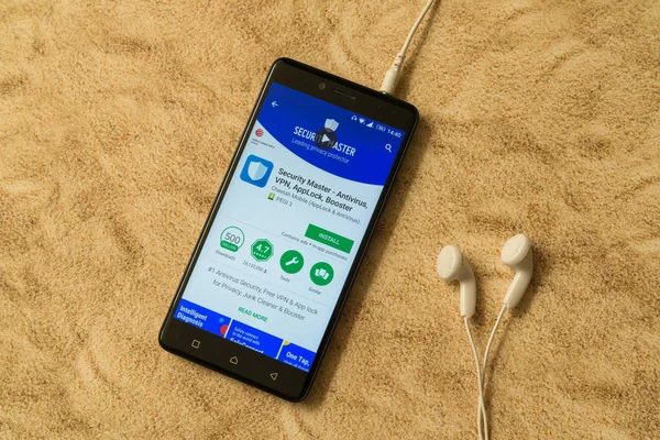 Безопасность мастер-приложение в Google Play Store на песчаном фоне и наушники — стоковое фото