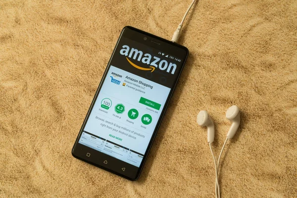 Aplicación Amazon en Google Play Store sobre fondo arenoso y auriculares — Foto de Stock