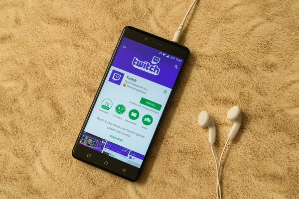 Aplicación Twitch en Google Play Store sobre fondo arenoso y auriculares — Foto de Stock