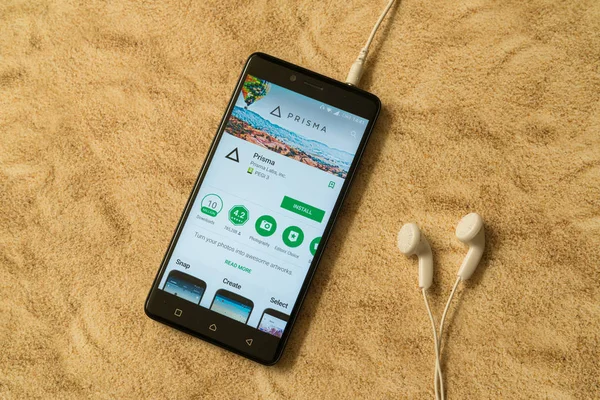 London, 14. November 2017: prisma Anwendung im google play store auf sandigem Hintergrund und Kopfhörer — Stockbild Prisma-Anwendung im Google Play Store auf sandigem Hintergrund und Kopfhörer — Stockfoto
