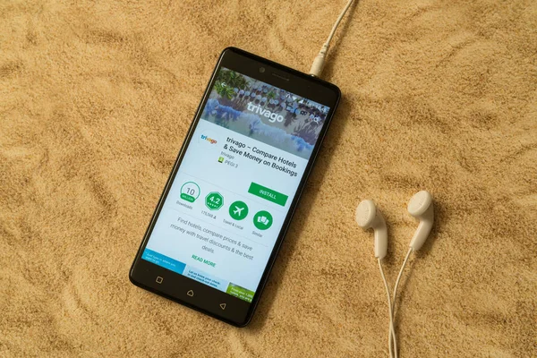 Aplicación Trivago en Google Play Store sobre fondo arenoso y auriculares — Foto de Stock