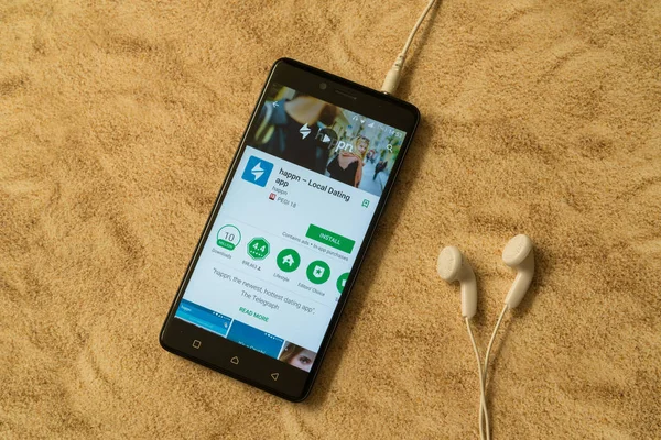 Aplicación Happn en Google Play Store sobre fondo arenoso y auriculares — Foto de Stock