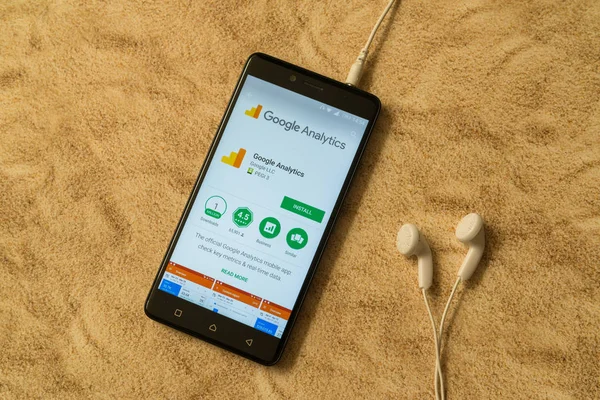 Google analytics-Anwendung in google play store auf sandigem Hintergrund und Kopfhörer — Stockfoto