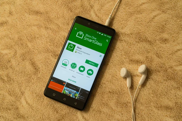 Xbox one smartglass Anwendung im google play store auf sandigem Hintergrund und Kopfhörer — Stockfoto