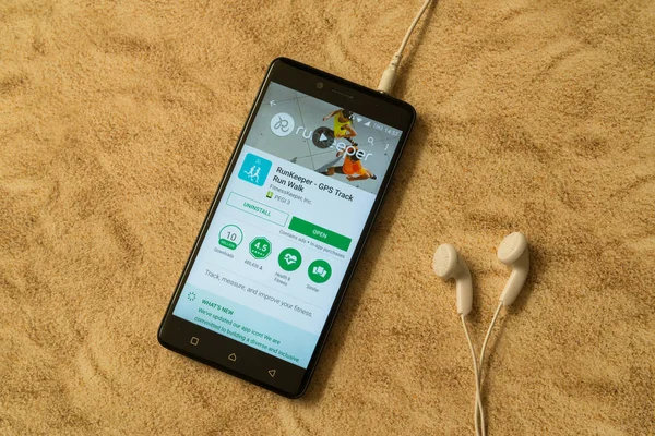 Runkeeper-Anwendung im Google Play Store auf sandigem Hintergrund und Kopfhörer — Stockfoto