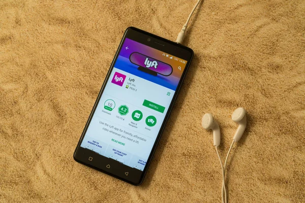 Лифт приложение в Google Play магазин на песчаном фоне и наушники — стоковое фото
