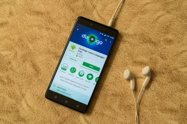 Aplicación Duolingo en Google Play Store sobre fondo arenoso y auriculares — Foto de Stock