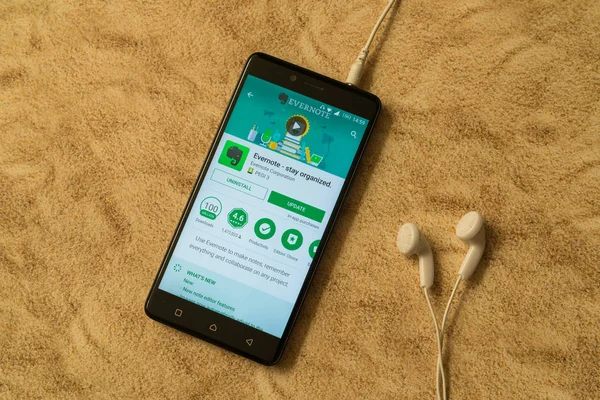 Evernote-Anwendung im Google Play Store auf sandigem Hintergrund und Kopfhörer — Stockfoto