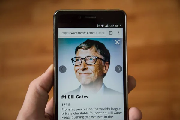 Londra, 31 Aralık 2017: Bill Gates forbes Web, cep telefonu sürümü. El ahşap arka plan ile akıllı telefon tutarak