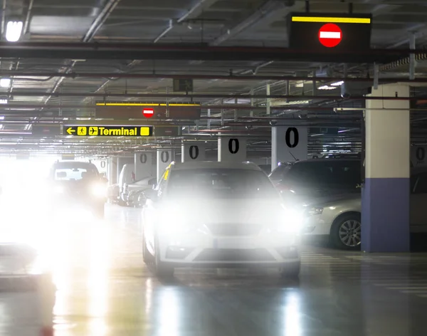 Indoor car park at airport, cars with blinding headlights