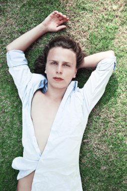 Genç adam çimenlerde yatıyor.