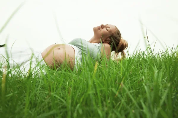 Mulher grávida relaxante na grama — Fotografia de Stock