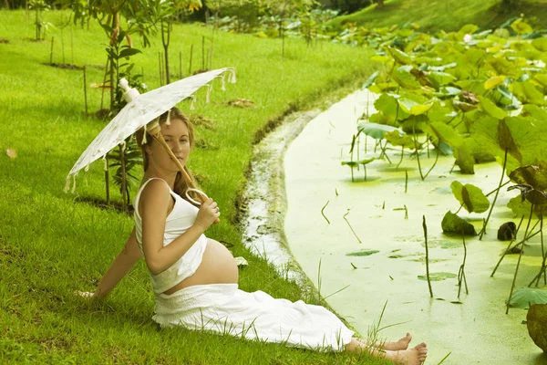 Femme enceinte assise près d'un lac — Photo