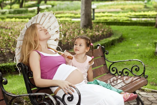 Gravid mor och dotter som sitter på en bänk — Stockfoto