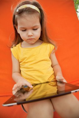 Çocuk bir tablet bir tembel üzerinde tutar.