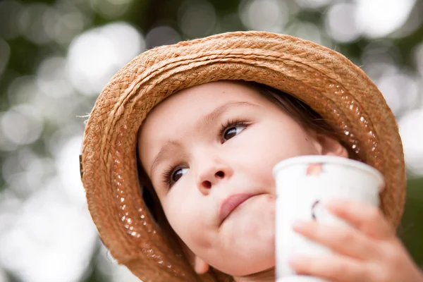 Маленькая девочка пьет из стакана — стоковое фото