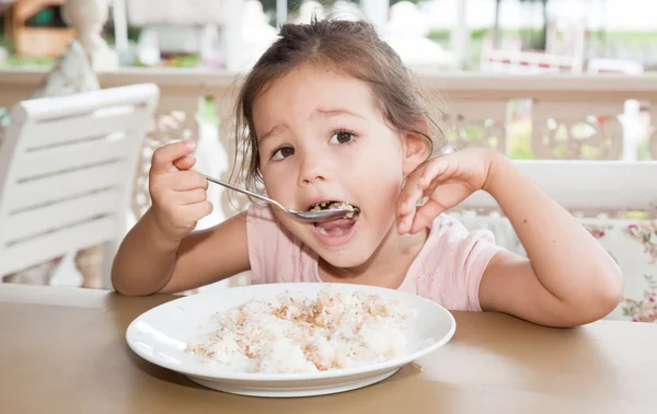 Küçük kız pirinç yiyor — Stok fotoğraf
