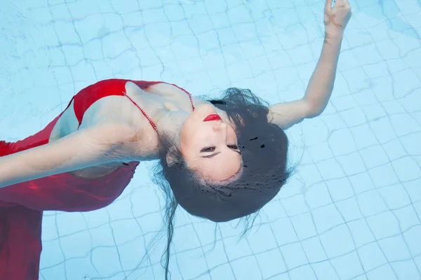 Donna in abito rosso nuotare in piscina — Foto Stock
