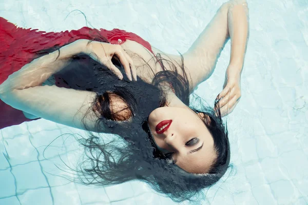 Egy piros ruhás, úszás a medencében nő — Stock Fotó