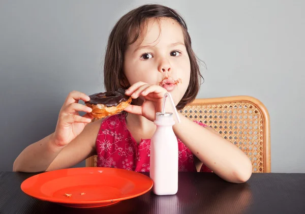Asyalı kız süt ile bir donut yemek — Stok fotoğraf