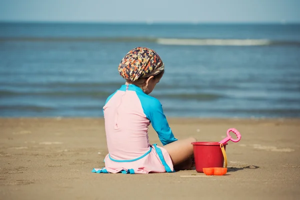 Meisje zitten op het strand — Stockfoto