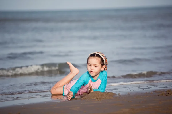 Flicka bygga sandslott på stranden — Stockfoto